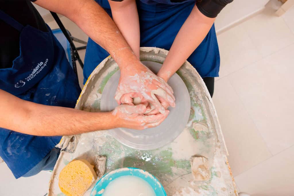 Hands shaping clay on a pottery wheel during a workshop.